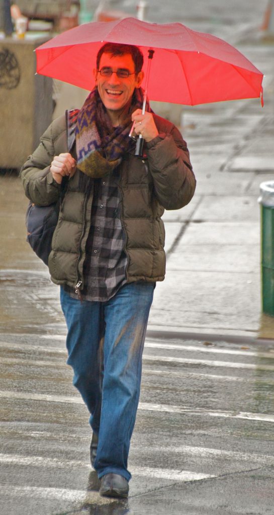 Cities Rewrite Their Playbooks for Extreme Weather People with umbrellas crossing a rainy city street