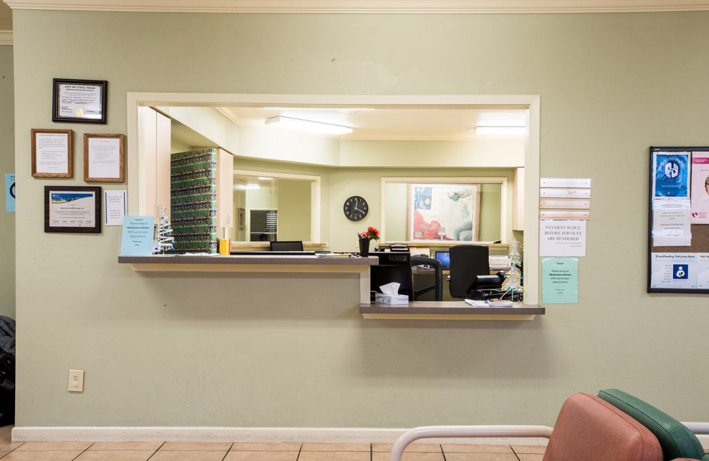 Patients sit in a bright community clinic waiting room before their appointments.