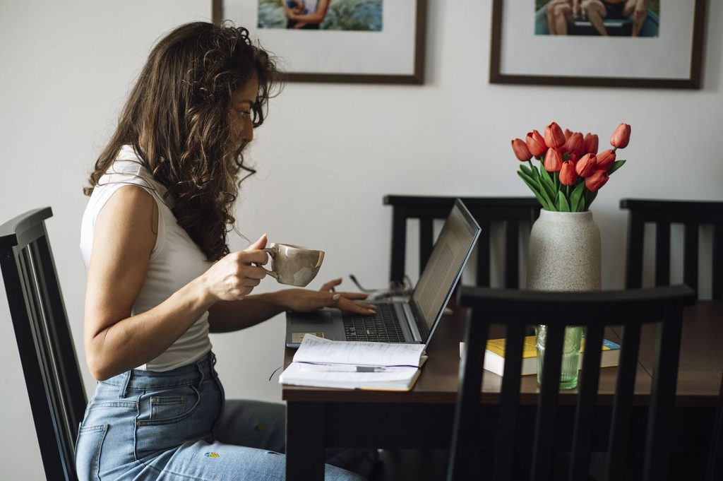 Creators Are Leaving Social Platforms for Newsletters and Owned Audiences Creator writing on a laptop at home while holding a cup of coffee